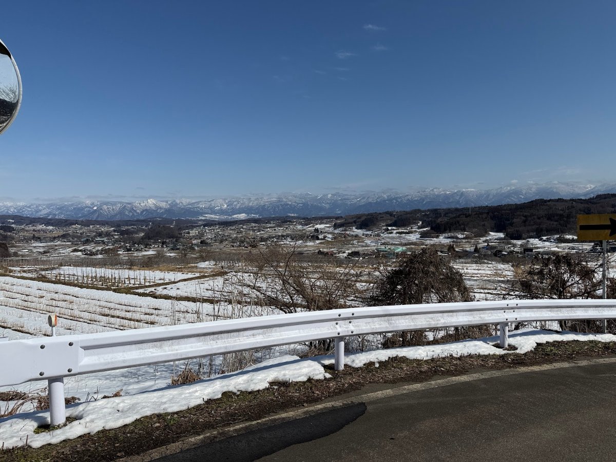 冬晴れの飯綱町。雪の残る畑と遠くの山並み