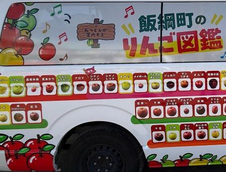 「飯綱町のりんご図鑑」の車体に並ぶりんごの品種